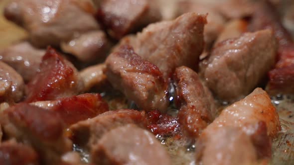 Pieces of Pork are Fried Closeup in a Pan in Slow Motion