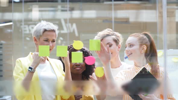 Creative Glamour Team Writing on Stickers at Office Glass Wall