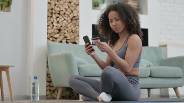 Online Payment on Smartphone By African Woman on Fitness Mat