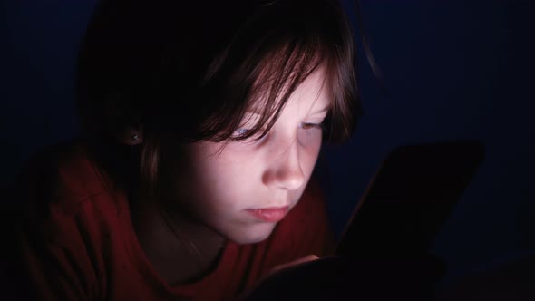 Little Girl Playing Online Games on Phone at Night