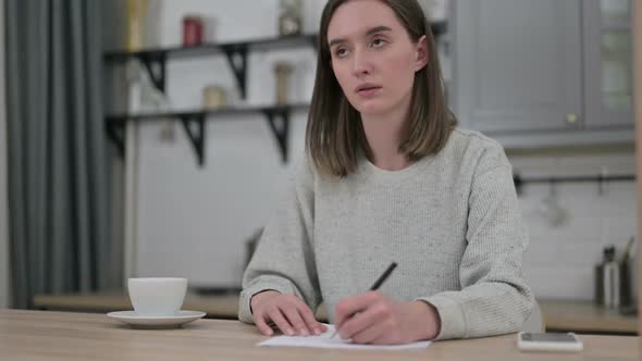 Focused Young Woman Thinking and Doing Paperwork at Home