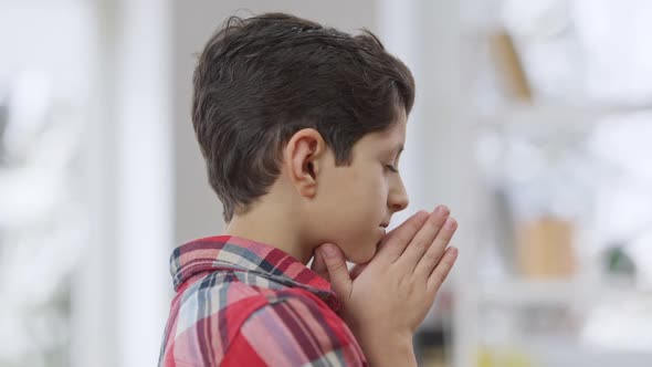 Side View Closeup of Little Middle Eastern Boy Praying with Hands Clasped Together