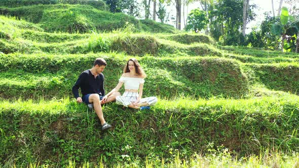 Young couple sitting in a rice field talking and enjoying each others company while on holiday