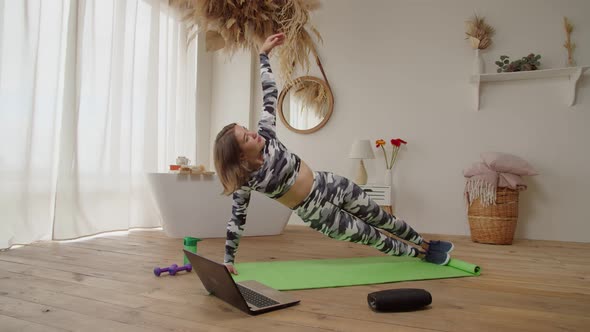 Pretty Active Sporty Fit Female Doing Side Plank Exercise Following Online Yoga Class Indoors