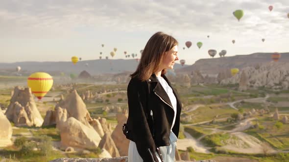 Young beautiful woman walking in front of Cappadocia landscape at sunset. Turkey	