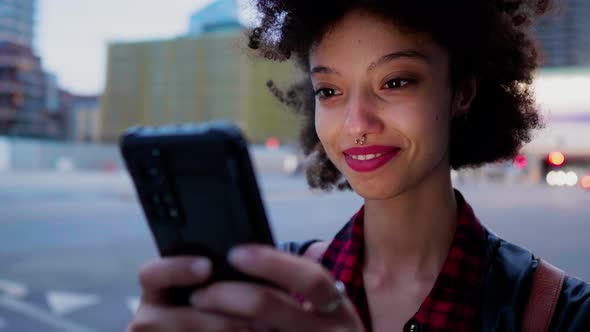 Young laughing woman using smartphone in the city