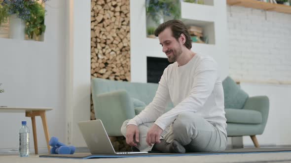 Young Man Talking on Video Call on Laptop Yoga Mat at Home