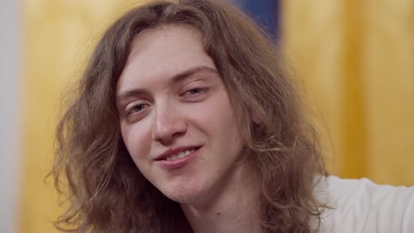 Headshot of Funny Confident Brunette Retro Man with Long Curly Hair Adjusting Eyebrows Looking at