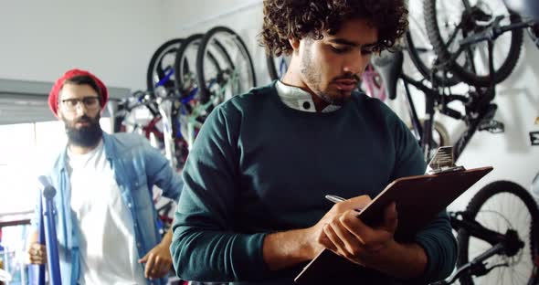 Mechanic writing on clipboard in workshop