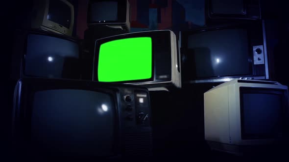 Retro TV Green Screen Amid Many Piled Television. Dark Tone. Zoom Out.