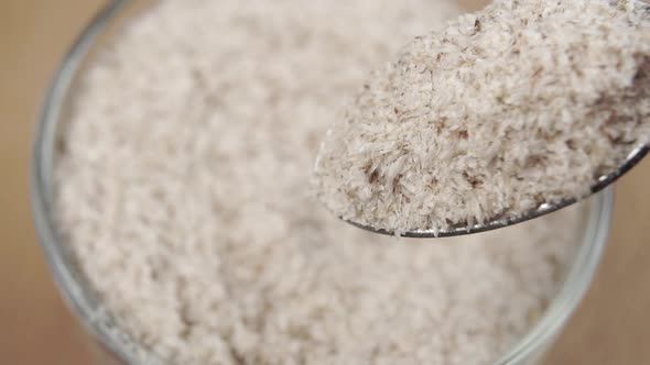 Natural herbal food supplement psyllium husk in a spoon. Falling in slow motion