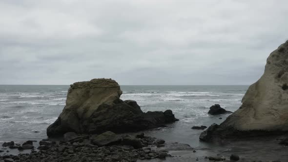 Aerial view flying between the rocky outcrops into the open pacific ocean 