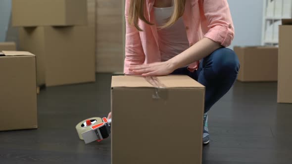Lady From Moving Service Carefully Packing Boxes With Stuff and Carrying Out