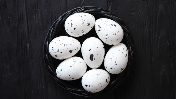 Whole Chicken Eggs in a Nest on a Black Rustic Wooden Background