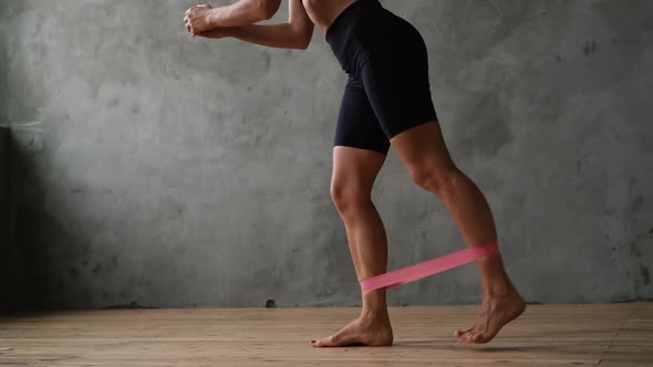 A Sports Girl in Sportswear Shakes Her Muscles with an Elastic Band