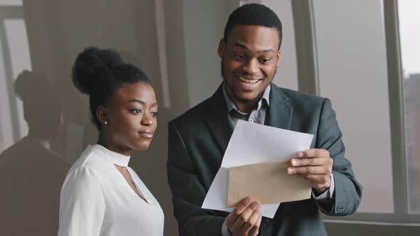 Happy Young African Businessman and Businesswoman Holding Papers Check Sales Statistics Looking at