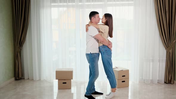 Couple Wearing Blue Jeans Hugs Kisses in Middle of New House