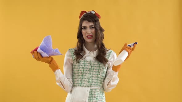 A Young Woman Holds a Rag and Spray in Her Hands with a Disgruntled Face