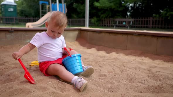 Adorable Toddler Girl Playing with Sand on Sandbox in Playground