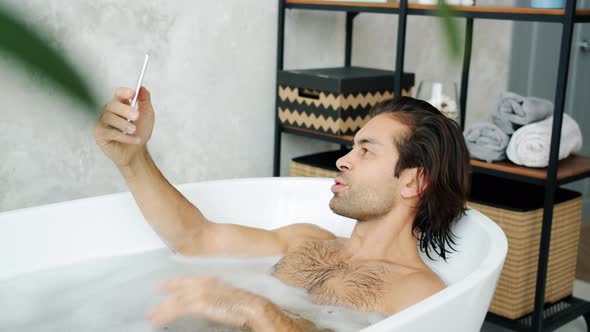 Happy Man Making Online Video Call Taking Bath Talking and Waving Hand in Bathroom