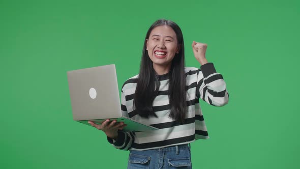 A Happy Asian Woman Celebrating While Using Computer On The Green Screen Background