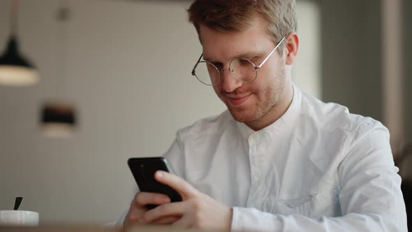 Attractive Man with Glasses is Viewing Funny Pictures and Video in Social Media on Smartphone