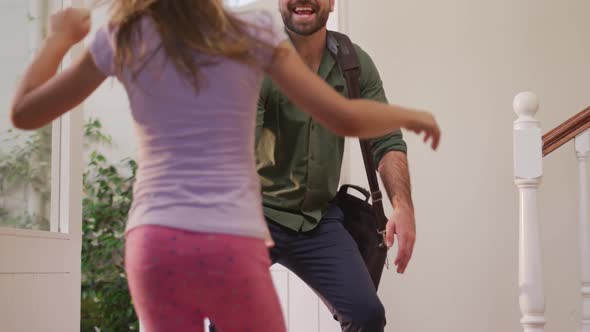 Caucasian man entering the front door of his house, greeting his daughter