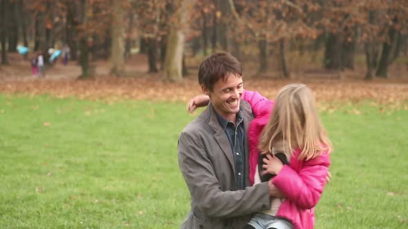 Girl running into father's arms in park