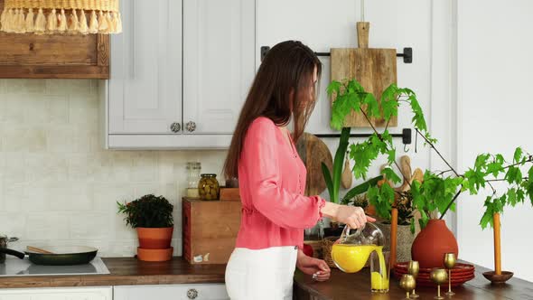 Young Girl Enters The Kitchen And Pours Juice In Glass