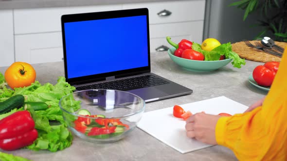 Blue Screen Laptop Woman Housewife in Kitchen Slices Tomato Listen Tells Chef