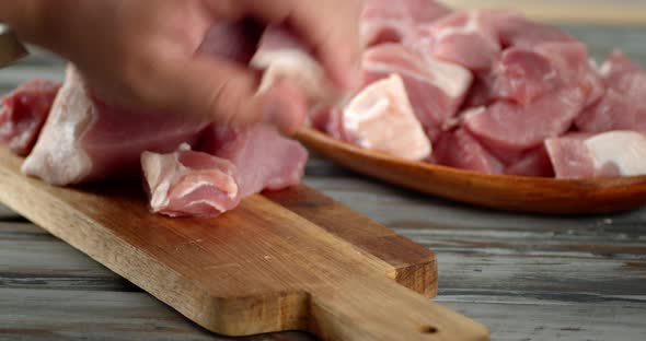 Men's Hands with a Knife Slice Raw Pork for Kebab.