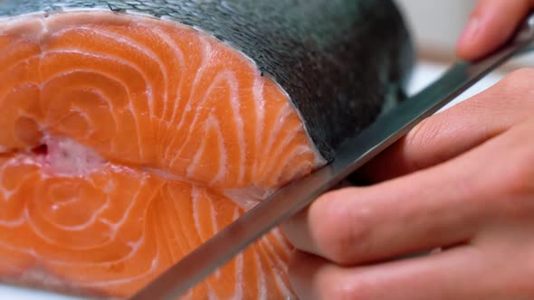Male Chef Cuts Slicing a Fresh Salmon Fillet in the Sushi Bar Restaurant