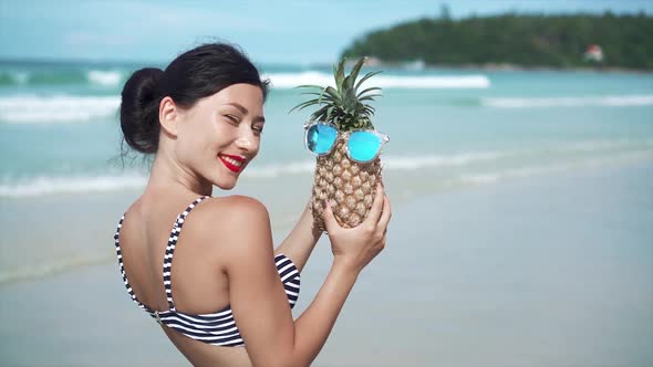 Woman Having Fun with a Pineapple in Sunglasses