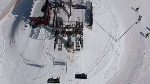 Aerial Top View of Ski Lift for Transportation Skiers on Snowy Ski Slope. Drone Flies Over Chair