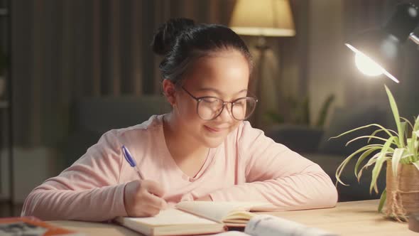 Teenage Girl Doing Homework At Table In Evening