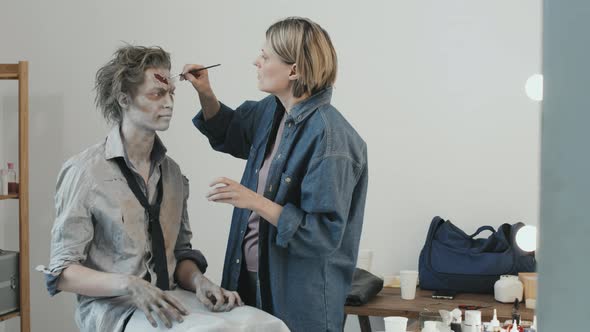 Woman Doing SFX Zombie Makeup on Man