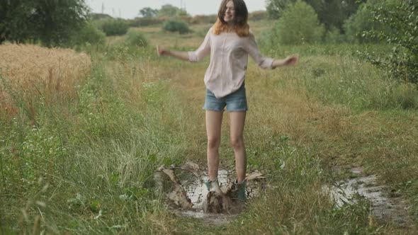 Beautiful Smiling Teen Girl Jumping in Very Muddy Puddle