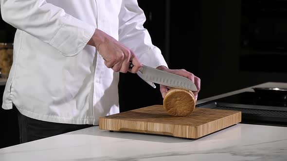 Professional chef cuts burger bun in restaurant kitchen with sharp knife