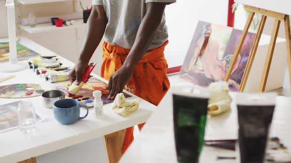 Midsection of african american male painter mixing paint in artist studio