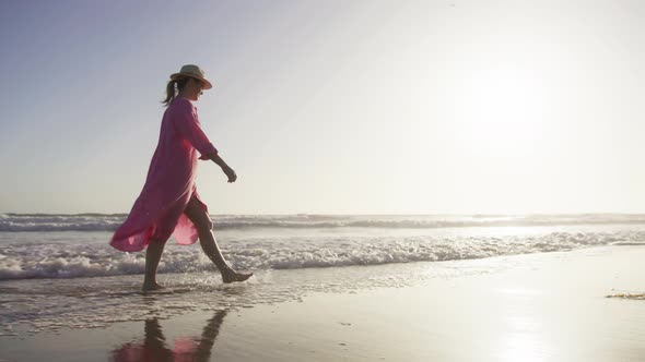 Silhouette Woman in Flying in Wind Pink Dress at Golden Sunset in Clear Blue Sky