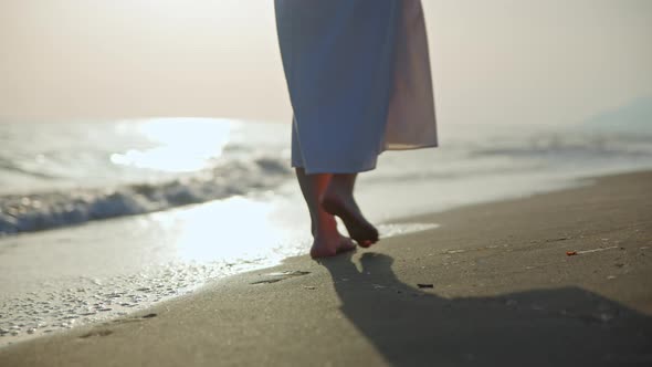 Young girl in a dress walking along the beach