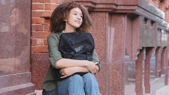 Young Attractive African American Girl with Curly Hair Wearing Jeans and Sneakers Holding Travel