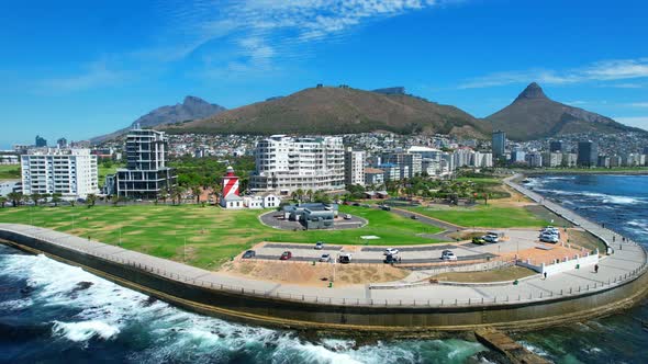People cycling at waterfront promenade park in Green Point on a sunny summer day with lions head in