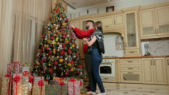 Young Mixed Couple Decorate Christmas Tree
