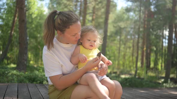 Little Cute Baby Toddler Girl Blonde with Curls on Mother's Arms