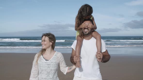 Happy Parents and Kid Walking on Beach