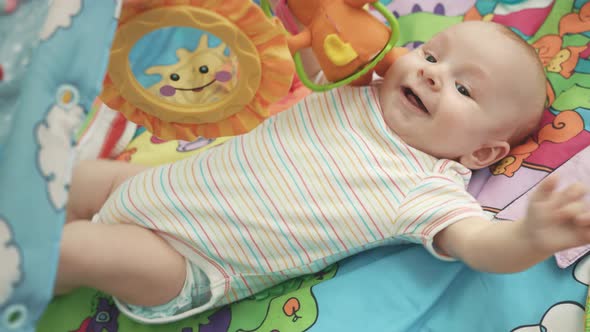 Joyful Baby Lying on Colorful Mat. Happy Infant Playing on Developing Mat