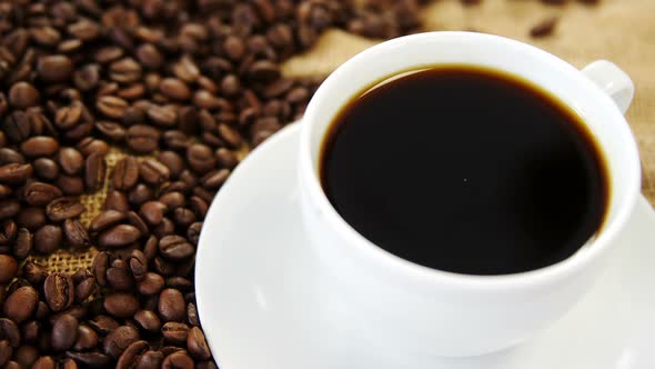 Coffee cup and roasted beans on sack textile