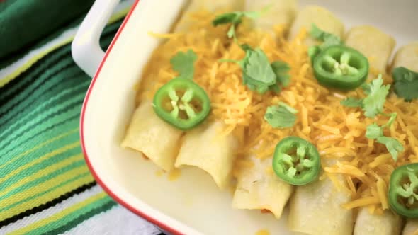 Chicken enchiladas with cheddar cheese and sauce.