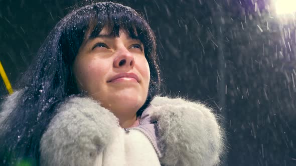 Happy Beautiful Girl Smiling Looking Up During Blizzard Snowfall. Young Adult